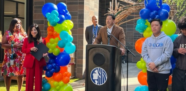 Mayor Bruce Harrell speaking at a podium beside Councilmember Maritza Rivera and others