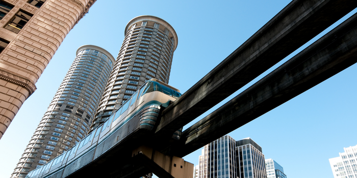View from below looking up at rail train with tall buildings in the background