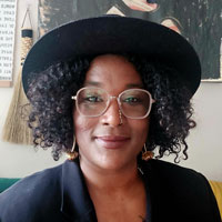 A Black woman wearing a hat and glasses