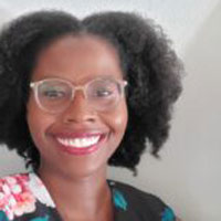 A Black woman with glasses and a floral blouse smiling