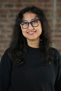 Shruti has long, wavy hair and wears dark glasses.