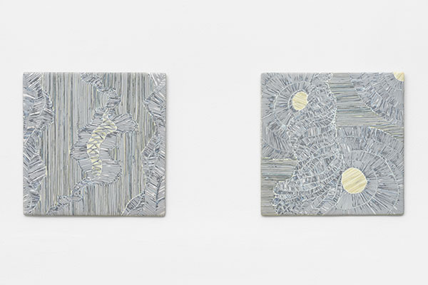Two square art works, mostly white with marks of black and gold.