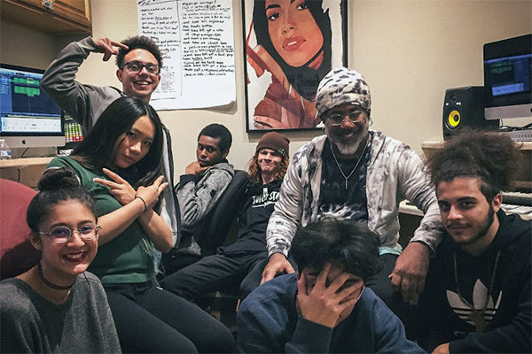 Youth crammed into a studio for a group photo with their mentor