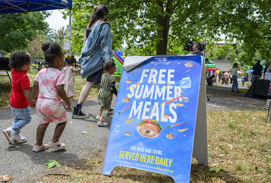 Kids enter park with Free Summer Meals sign.