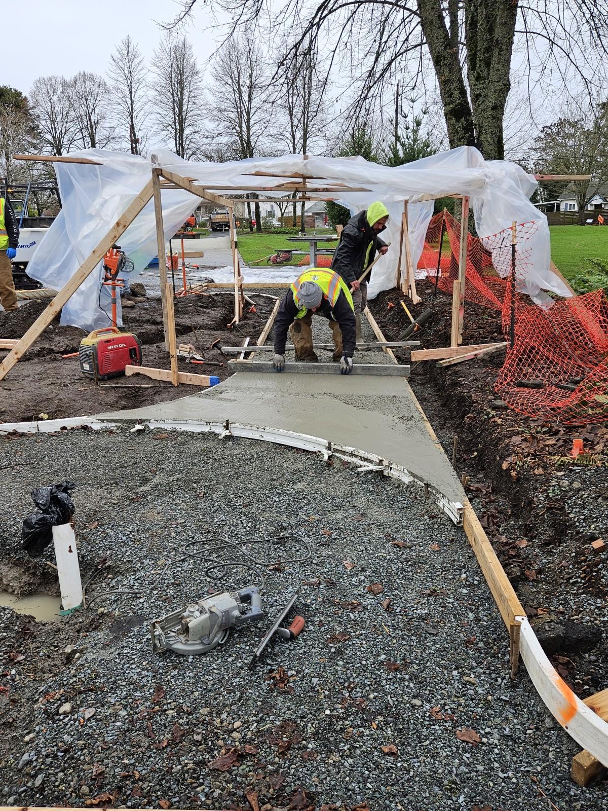 A Corps member smooths and levels a section of wet cement.