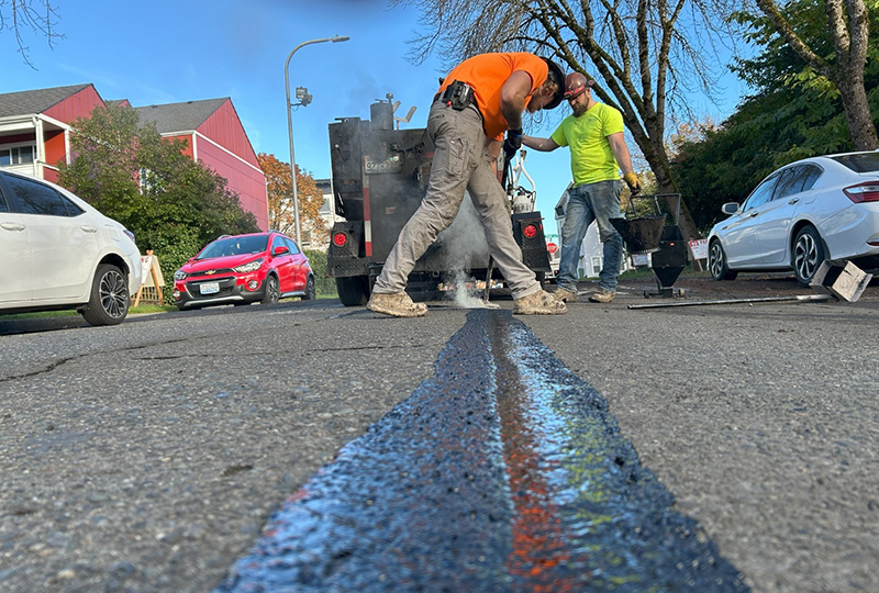 Two workers performing pavement repairs