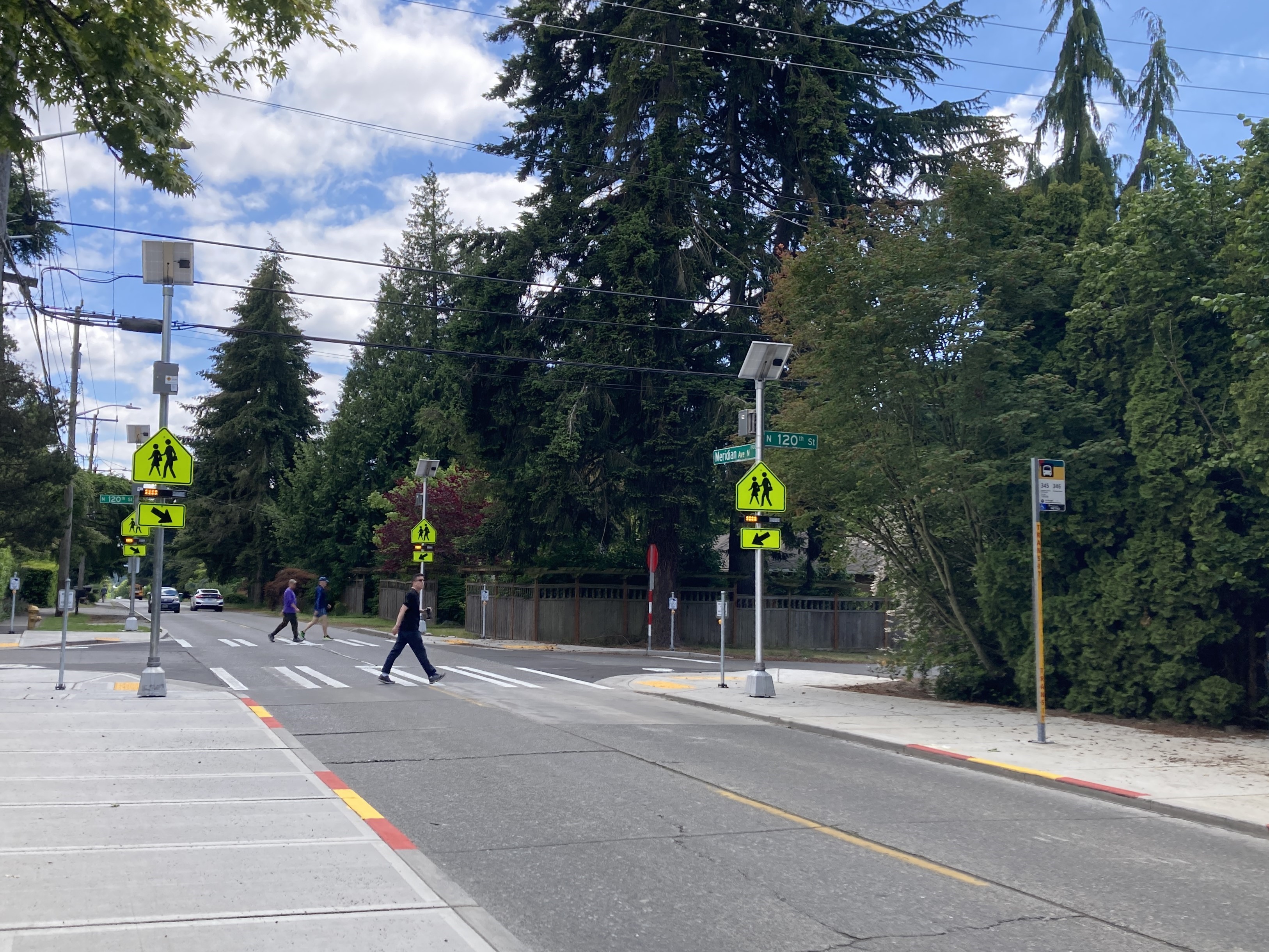A person crossing the street in a crosswalk next to yellow pedestrian crossing signs 