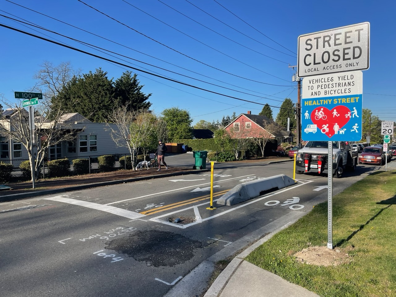 Photo of a street closed sign next to a street with a bike lane and lanes and concrete median