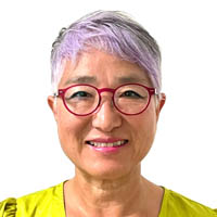 Regina has purple and gray hair, red glasses, and a yellow shirt