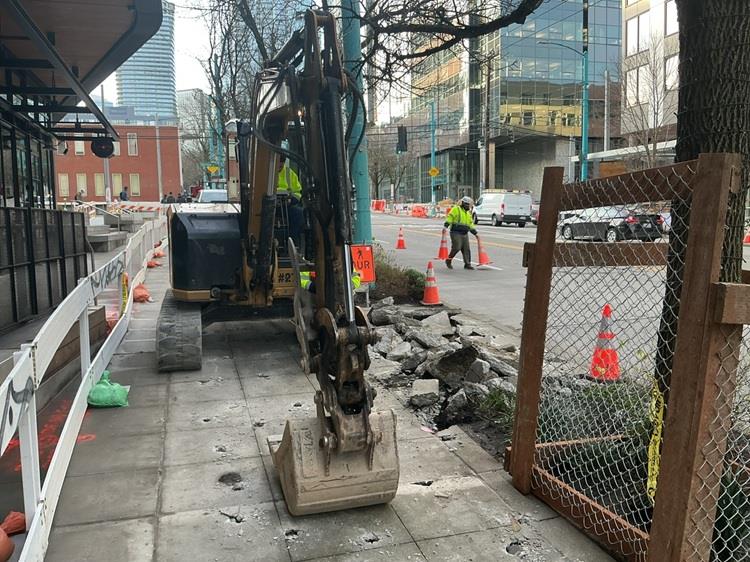Image shows the construction team breaking up the old sidewalk on along Fairview Ave to install new electrical supply to new bus stops