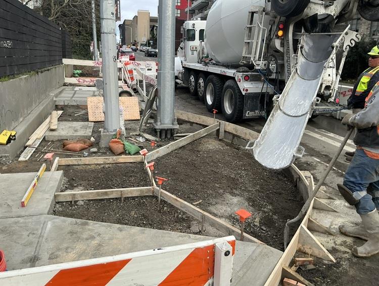 Image shows the team pouring new concrete for new pedestrian curb ramps in the University District
