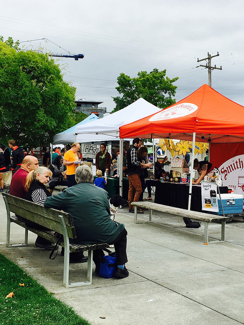 Adults sitting on a bench observing a farmer's market