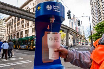 A person filling a bottle at a water refill station.