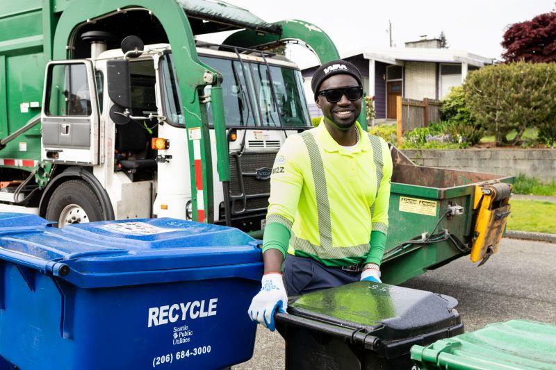 A worker collecting a garbage bin.