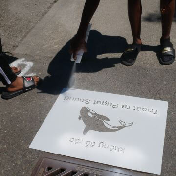 A volunteer spray paints a stencil in Vietnamese.