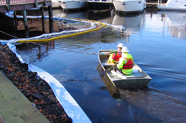 Spill response team in a small boat with cleanup equipment.