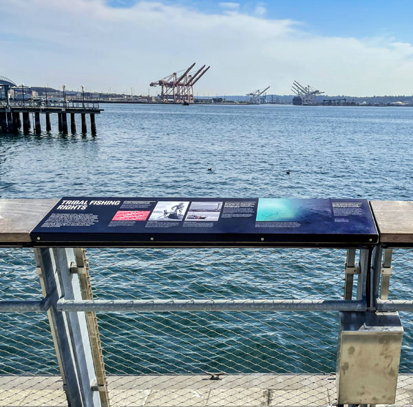 A placard along a pier rail that tells the story of tribal fishing rights