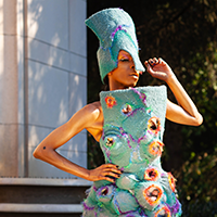 Model Adé Cônnére wearing a turquoise garment composed of acrylic wool and steel wire made to look like a coral reef.