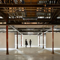 Exposed steelwork reflected in a shiny concrete floor. Kinetic walls float above.