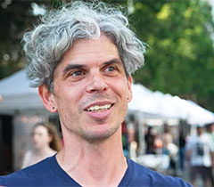 Aaron has curly, gray hair and speaks from the street festival.