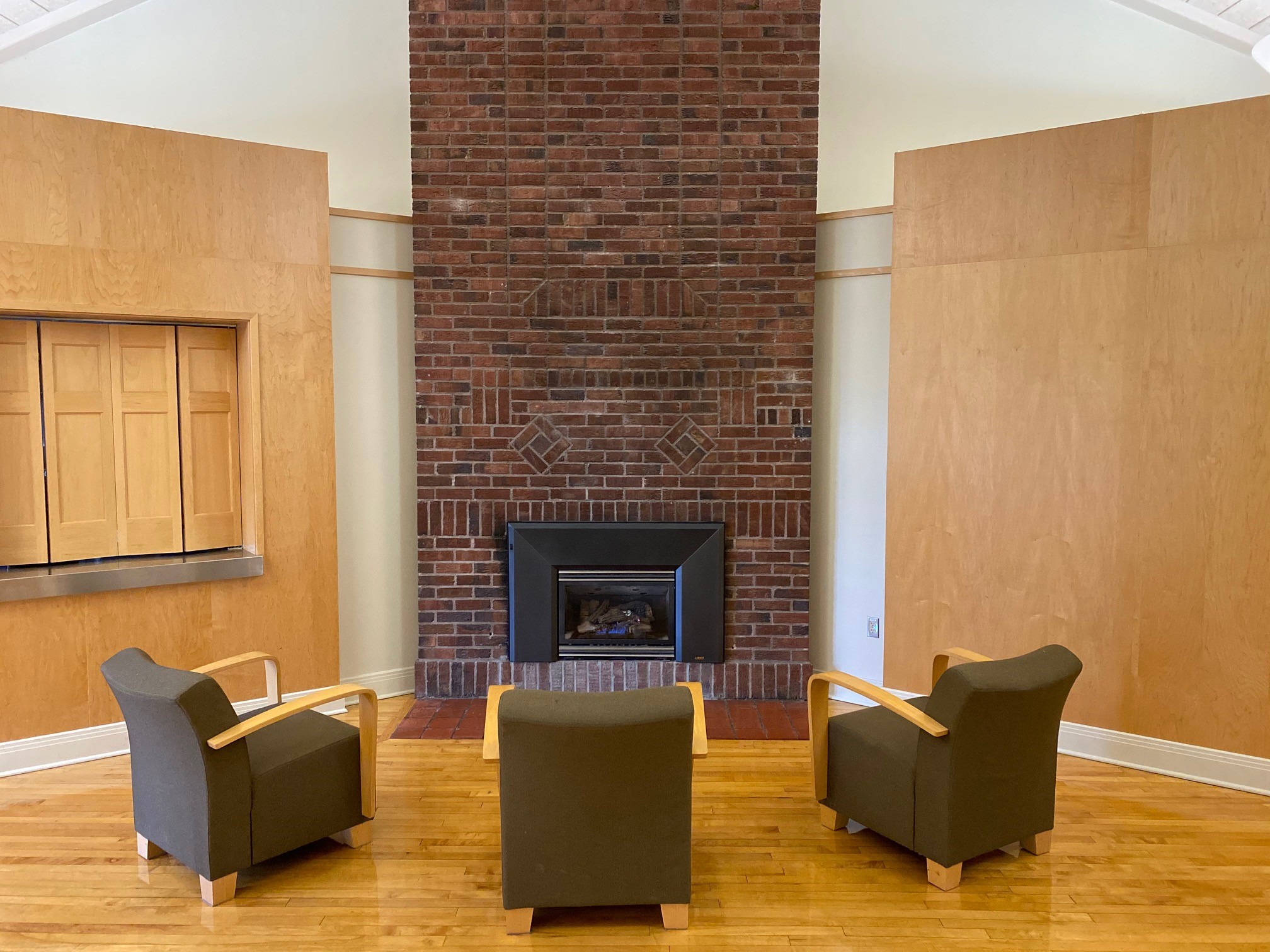 A cozy fireplace with three chairs before it, facing the fire.
