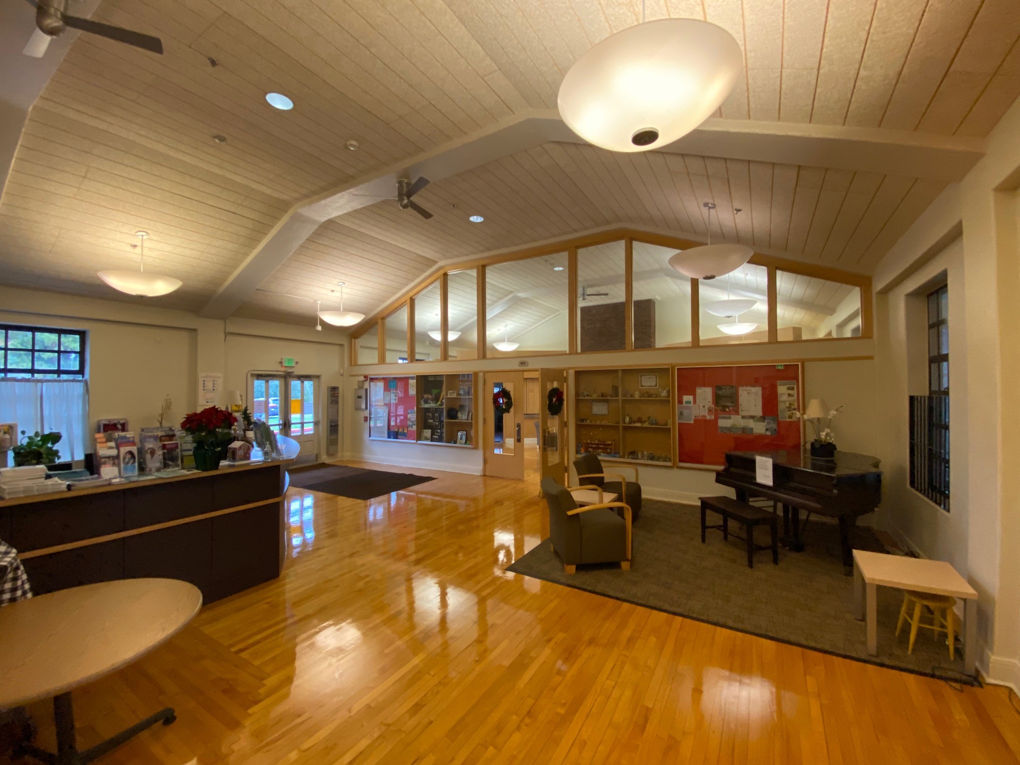 A large open room with ceiling lights, a high desk, and furniture, typical of a building lobby.