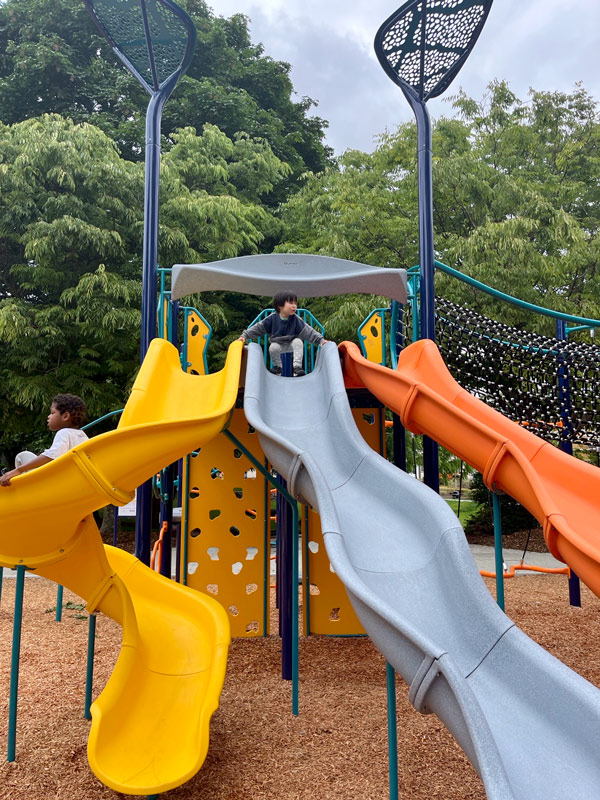 Spruce Street Mini Park Slides - Children sliding down three slides in play area