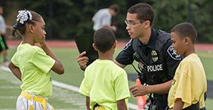 Image of Cop surrounded by 3 kids all having fun