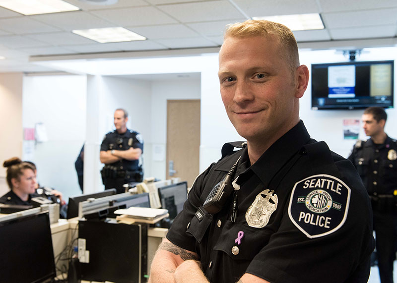 Police officer standing in the office near other coworkers