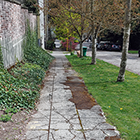 Sidewalk with severe cracking along a steep slope.