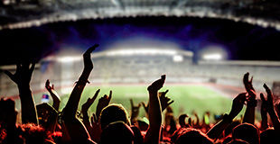 Group of fans cheering in a stadium at night
