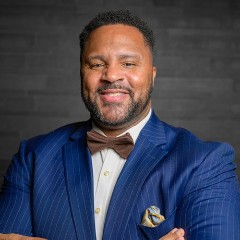 Chief of Staff William Smith smiling in a blue and white suit.